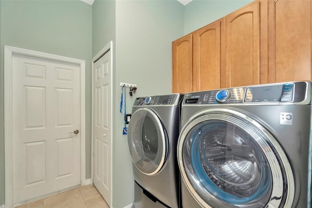 laundry area featuring light tile patterned floors, washer and clothes dryer, and cabinets