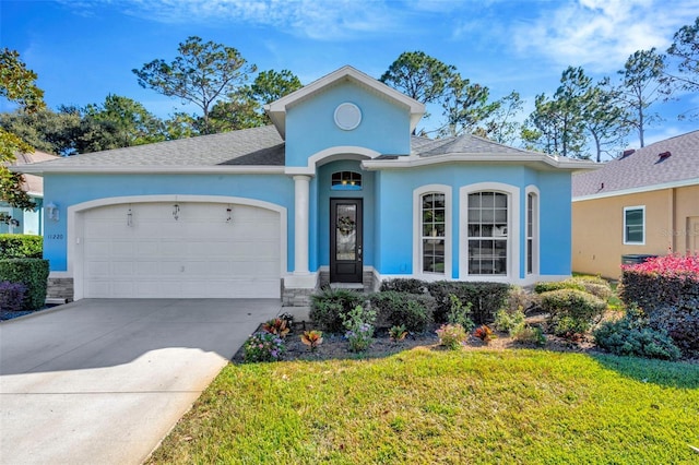 ranch-style home featuring concrete driveway, an attached garage, stucco siding, and a front lawn