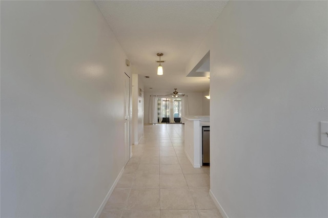 corridor with light tile patterned floors and a textured ceiling