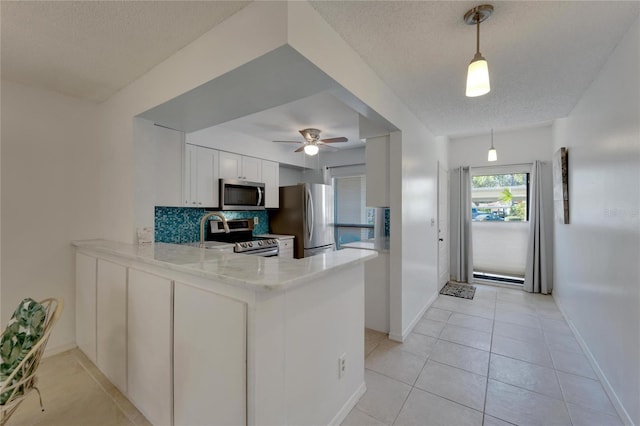 kitchen featuring kitchen peninsula, appliances with stainless steel finishes, a textured ceiling, pendant lighting, and white cabinets