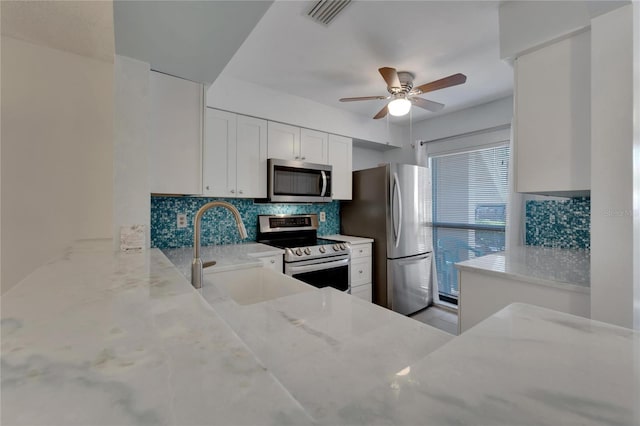 kitchen featuring white cabinetry, sink, stainless steel appliances, tasteful backsplash, and light stone counters