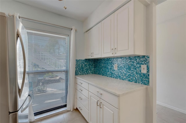 kitchen featuring white cabinets, stainless steel fridge, decorative backsplash, and light tile patterned floors