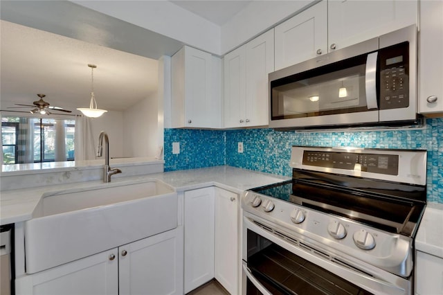 kitchen with backsplash, sink, ceiling fan, white cabinetry, and stainless steel appliances