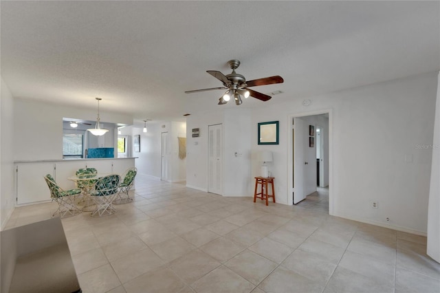 unfurnished living room featuring ceiling fan, light tile patterned flooring, and a textured ceiling