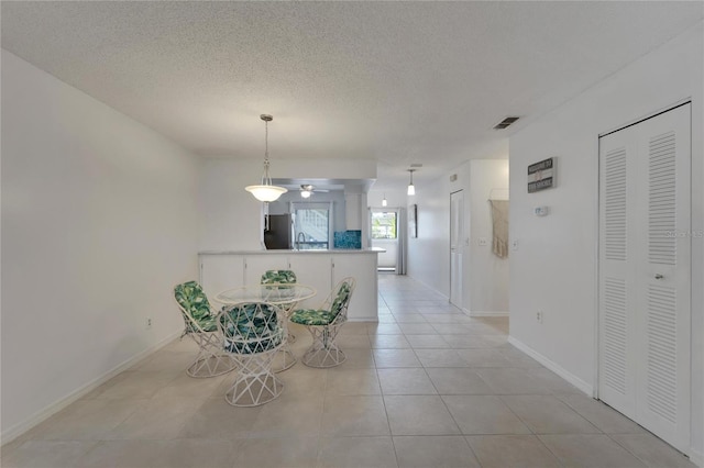 unfurnished dining area with light tile patterned flooring, sink, and a textured ceiling