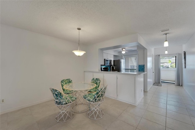 unfurnished dining area featuring a textured ceiling, ceiling fan, and light tile patterned flooring