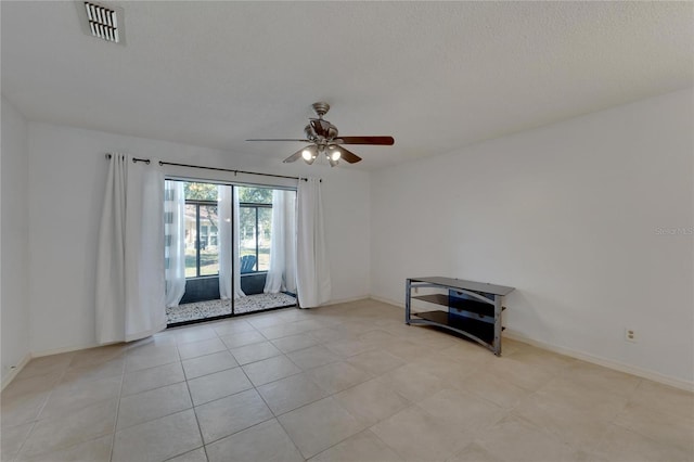 spare room featuring ceiling fan, light tile patterned flooring, and a textured ceiling