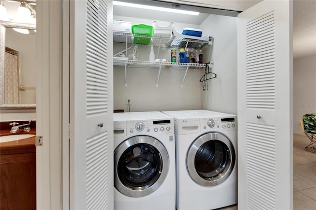 laundry area with washer and dryer, light tile patterned flooring, and sink