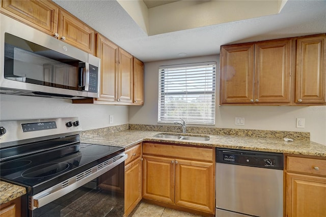 kitchen featuring light stone counters, sink, stainless steel appliances, and a textured ceiling