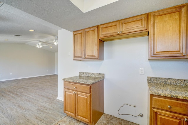 kitchen featuring light stone countertops, a textured ceiling, ceiling fan, light hardwood / wood-style flooring, and lofted ceiling