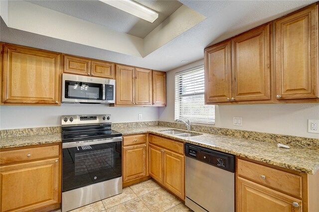 11339 Gulfstream Blvd, Port Charlotte, FL 33981 - kitchen with stainless steel appliances, light tile patterned flooring, light stone counters, and brown cabinetry