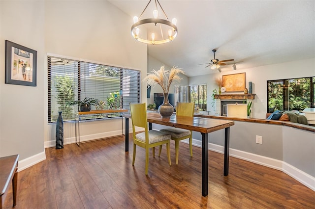 dining space with ceiling fan with notable chandelier, dark hardwood / wood-style floors, vaulted ceiling, and a healthy amount of sunlight