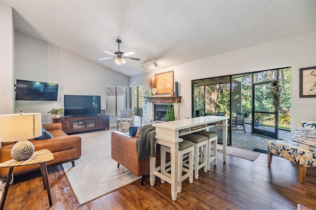 living room featuring a textured ceiling, ceiling fan, dark wood-type flooring, and lofted ceiling