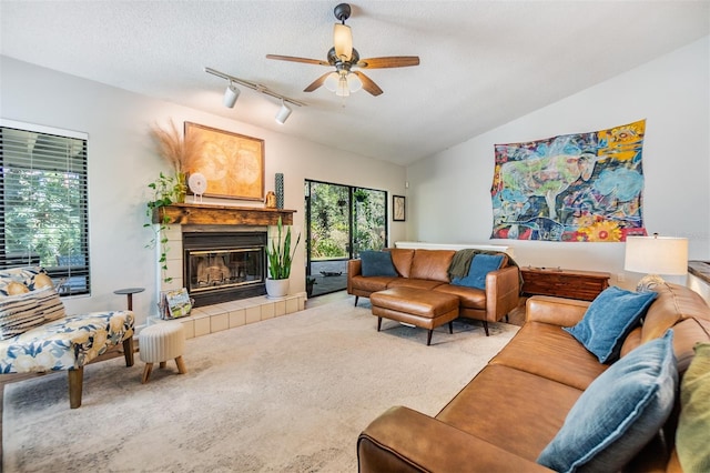 14631 Village Glen Cir, Tampa, FL 33618 - carpeted living room with rail lighting, a ceiling fan, vaulted ceiling, a tiled fireplace, and a textured ceiling