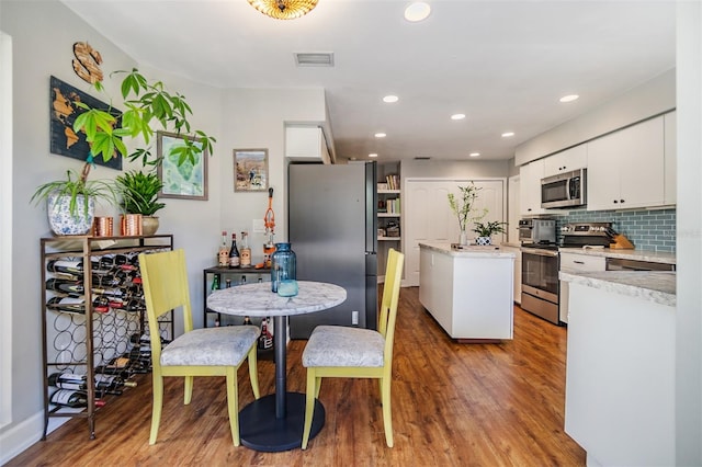 kitchen featuring a center island, white cabinets, appliances with stainless steel finishes, tasteful backsplash, and light hardwood / wood-style floors