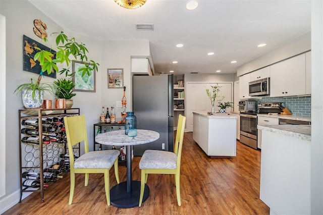 14631 Village Glen Cir, Tampa, FL 33618 - kitchen featuring appliances with stainless steel finishes, a center island, wood finished floors, light countertops, and white cabinetry
