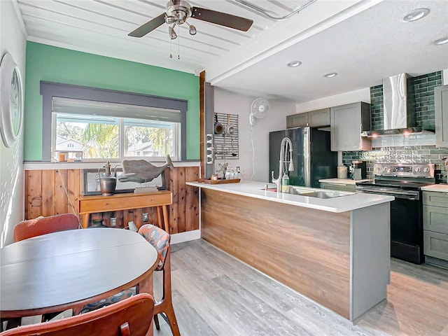 kitchen featuring gray cabinetry, wall chimney range hood, sink, light hardwood / wood-style flooring, and appliances with stainless steel finishes