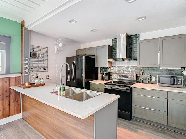 kitchen featuring backsplash, wall chimney range hood, sink, appliances with stainless steel finishes, and light hardwood / wood-style floors