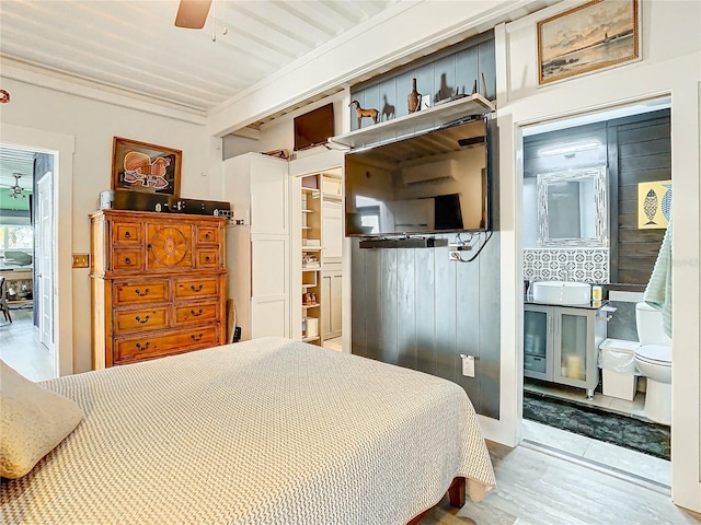 bedroom featuring ceiling fan, crown molding, hardwood / wood-style flooring, connected bathroom, and a closet