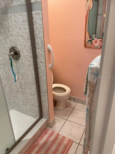 bathroom featuring tiled shower, tile patterned flooring, and toilet