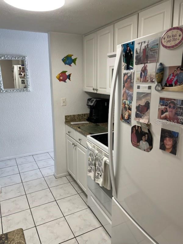 4199 38th Ave S Unit I, Saint Petersburg, FL 33711 - kitchen with white appliances, white cabinets, light tile patterned floors, and dark countertops