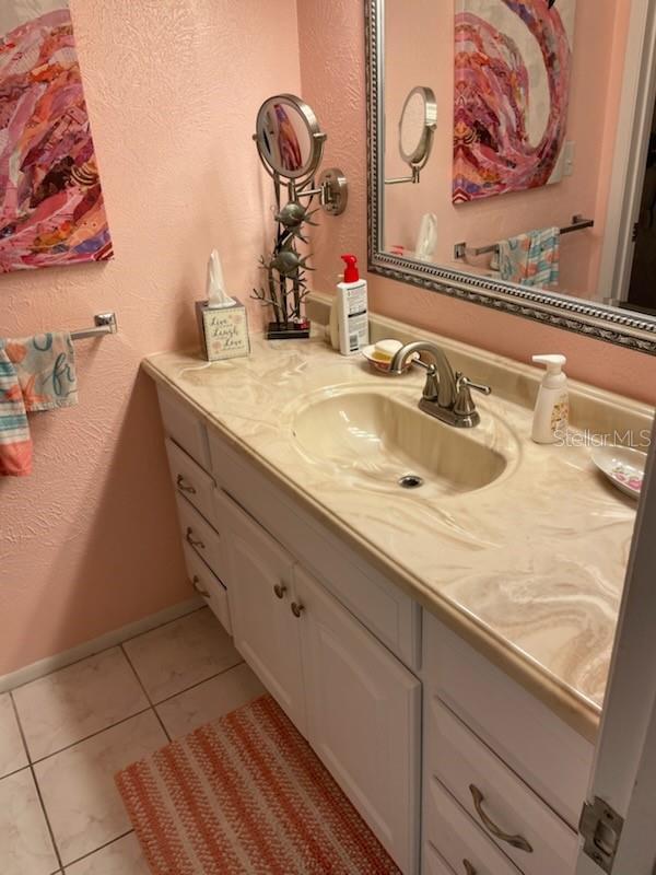 4199 38th Ave S Unit I, Saint Petersburg, FL 33711 - bathroom with vanity, tile patterned floors, baseboards, and a textured wall