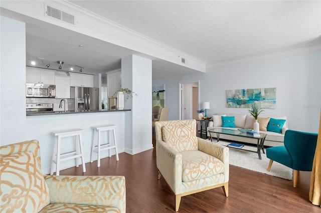 living room featuring crown molding, sink, track lighting, and dark hardwood / wood-style floors