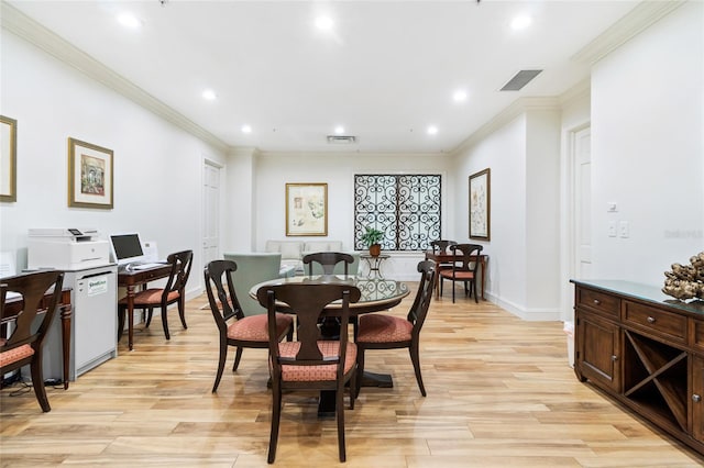 dining room with crown molding and light hardwood / wood-style flooring