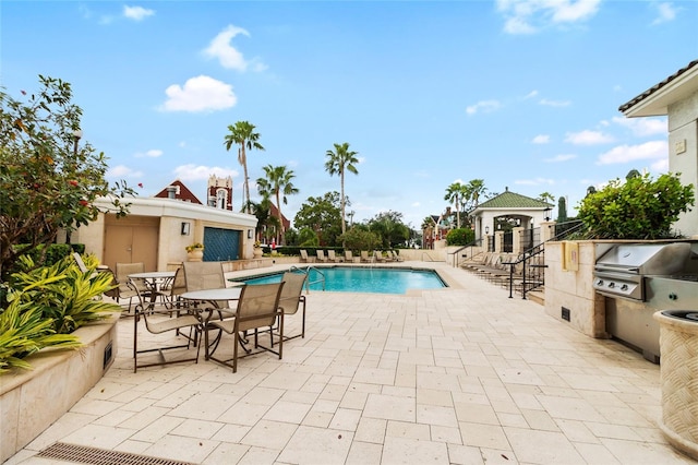 view of swimming pool featuring a patio area, an outdoor kitchen, and grilling area