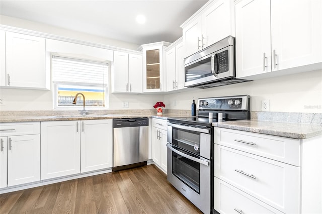 kitchen featuring sink, white cabinetry, wood-type flooring, stainless steel appliances, and light stone countertops