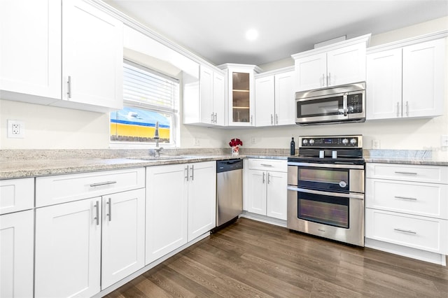 kitchen featuring appliances with stainless steel finishes, sink, white cabinets, dark hardwood / wood-style flooring, and light stone countertops