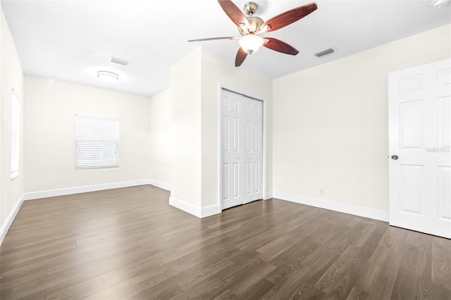 unfurnished bedroom featuring ceiling fan, dark hardwood / wood-style flooring, and a closet