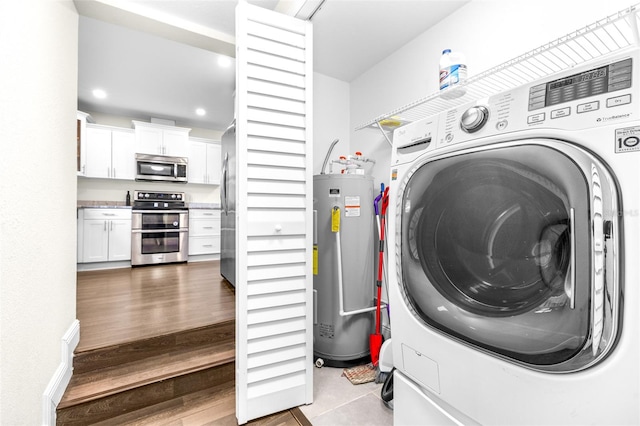 laundry room with washer / dryer, water heater, and light wood-type flooring