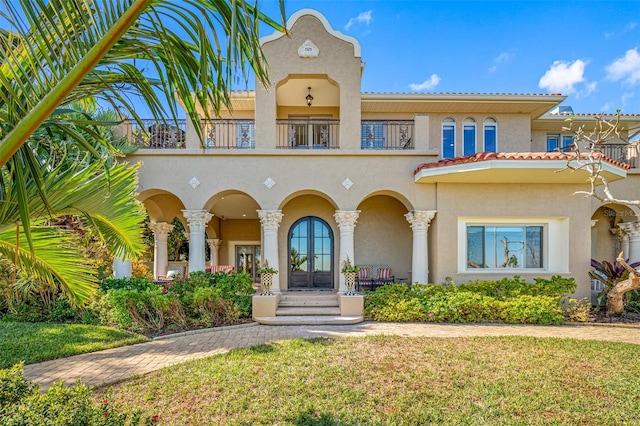 view of front of home with a front lawn, a balcony, and french doors