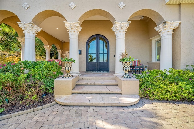 view of exterior entry featuring covered porch and french doors