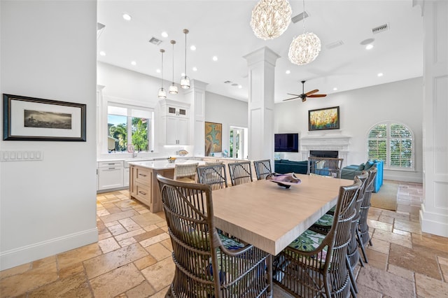 dining space featuring ceiling fan with notable chandelier, decorative columns, and a wealth of natural light