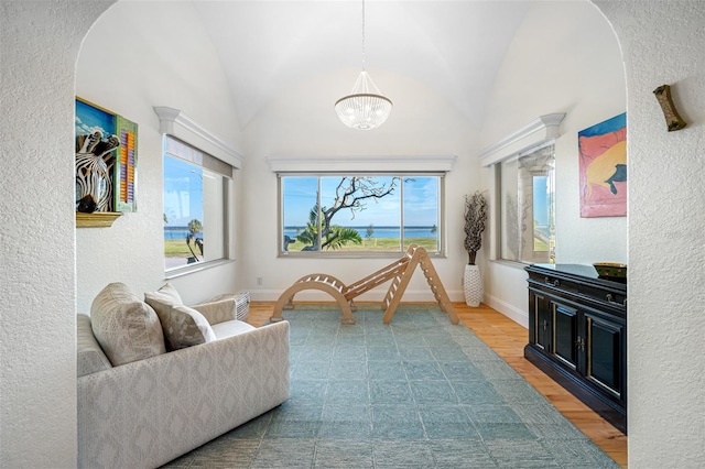 living area with hardwood / wood-style flooring, a notable chandelier, and lofted ceiling