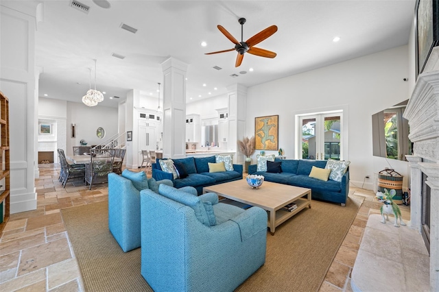 living room with ceiling fan with notable chandelier, decorative columns, and a high ceiling