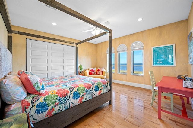 bedroom with ceiling fan, beam ceiling, light hardwood / wood-style floors, and a closet