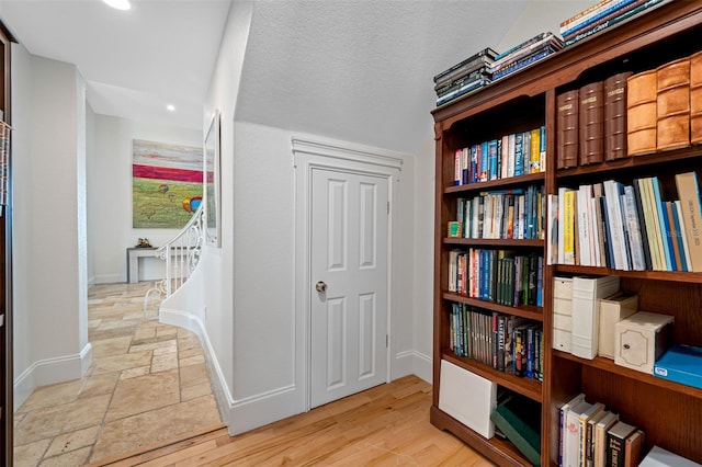 hall with a textured ceiling and light wood-type flooring