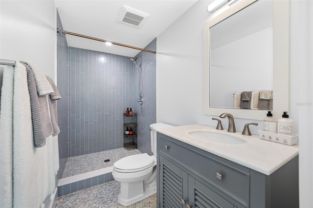 bathroom featuring tile patterned floors, vanity, tiled shower, and toilet