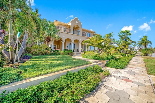 mediterranean / spanish-style house with a balcony and a front lawn