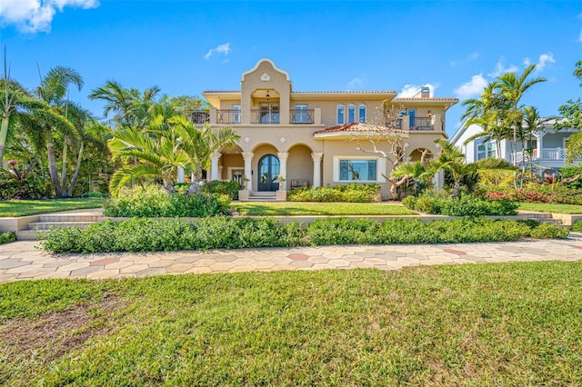 mediterranean / spanish-style house featuring a front lawn and a balcony