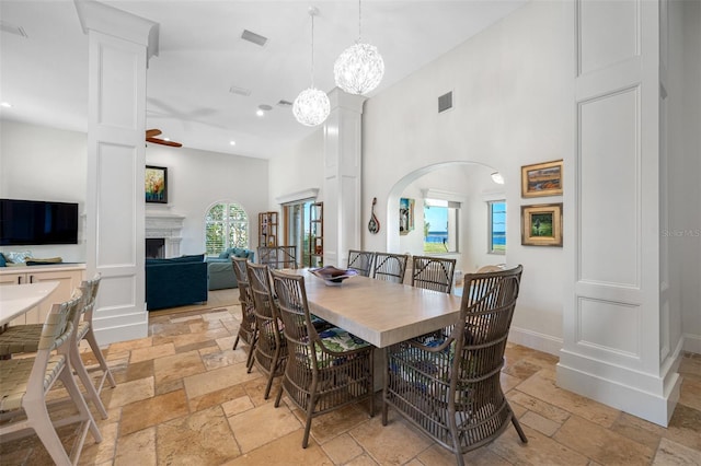 dining space featuring ceiling fan, high vaulted ceiling, and ornate columns