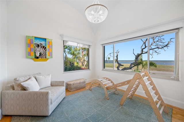 sitting room with a water view, lofted ceiling, wood-type flooring, and a chandelier