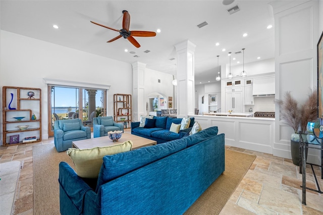 living room featuring ornate columns, a towering ceiling, and ceiling fan