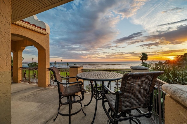 patio terrace at dusk featuring a water view