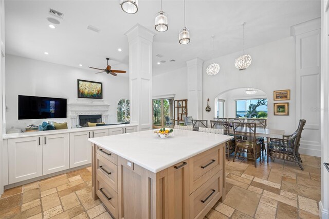 kitchen with a kitchen island, white cabinetry, hanging light fixtures, ceiling fan, and light brown cabinets