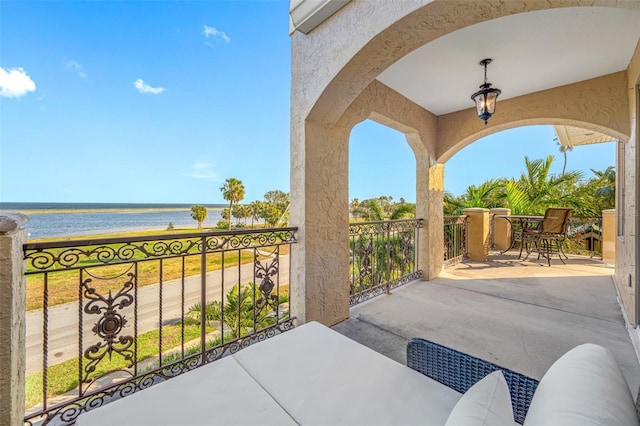 view of patio / terrace with a balcony and a water view