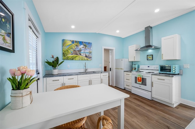 kitchen featuring wall chimney range hood, white appliances, sink, white cabinetry, and hardwood / wood-style floors